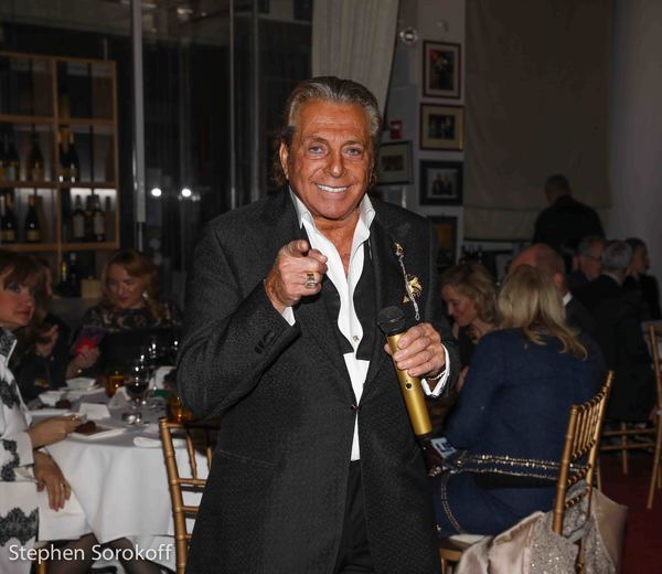 Gianni Russo smiling and holding a microphone at an event